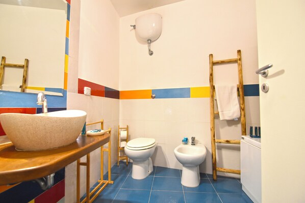 Un baño con un lavamanos tipo cuenco, inodoro, bidé y una escalera de madera.