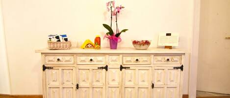 A white cabinet with drawers and a vase with flowers.