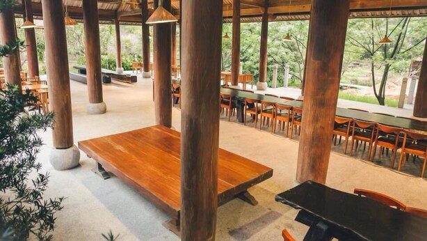 An indoor dining area with wooden tables and chairs, large pillars, and hanging pendant lights. - Quynh Vien Resort (Thach Khe)