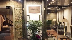Ein Hotel mit steinverkleideter Fassade, einer großen Pflanze im Topf und einem Schild mit der Aufschrift 'Hotel Garden'.