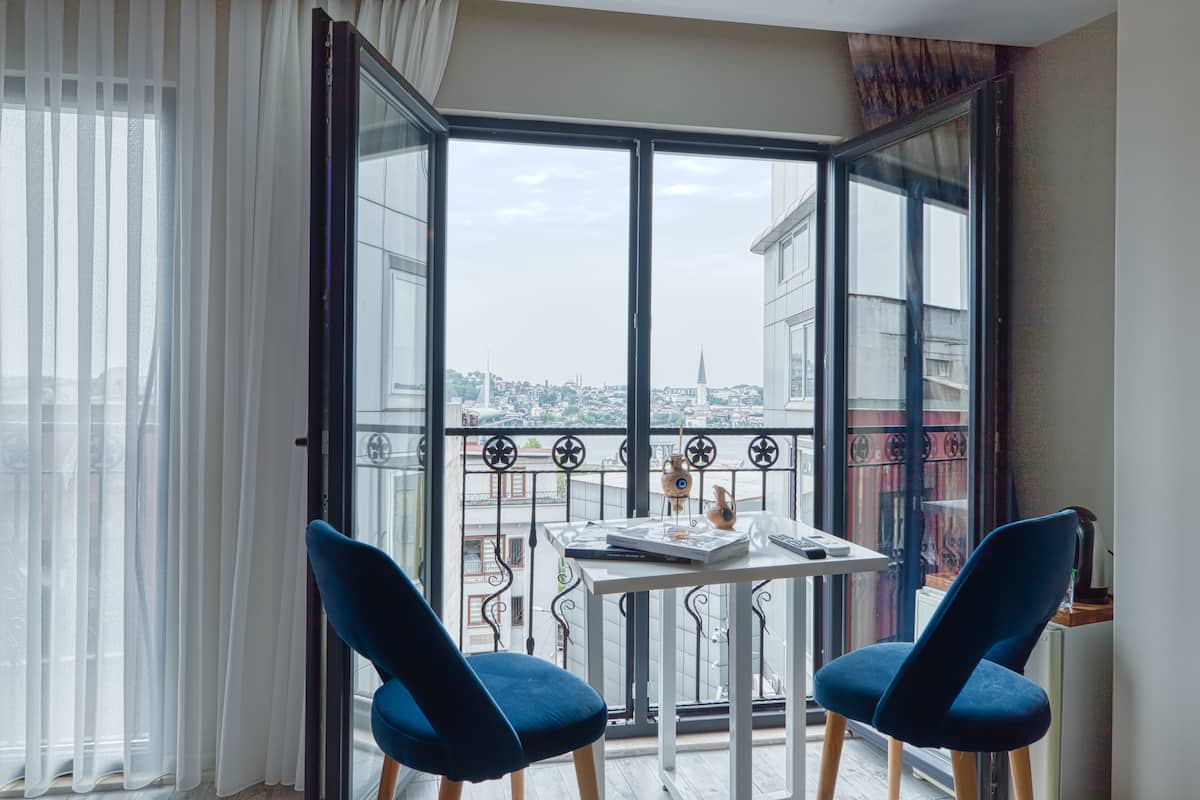 A balcony with a table and two chairs, overlooking a cityscape.