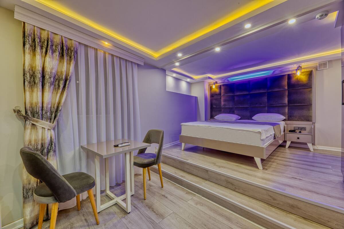 A modern bedroom with a bed, bedside tables, a desk, and chairs.