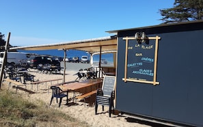 Ein Café direkt am Strand mit Außenplätzen, einer Speisekarte und Blick auf den Ozean.