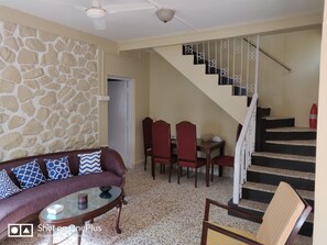 Relax in a stylish living area with a sofa, dining set, and staircase.