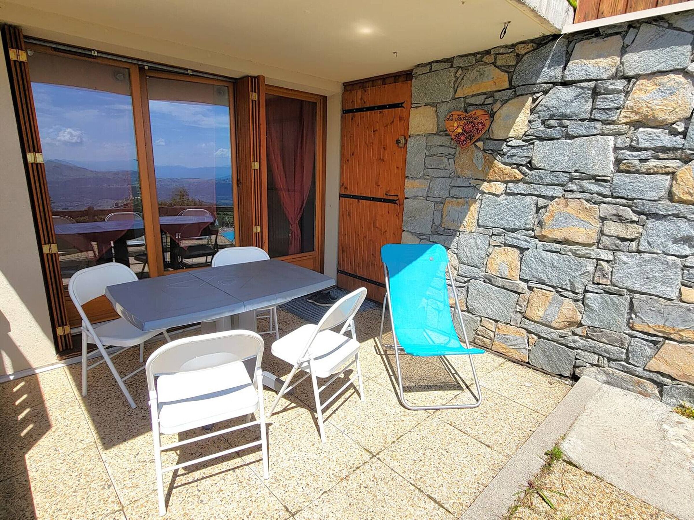 Eine Außenpatio mit Tisch und Stühlen, einer Steinmauer und Blick auf die Berge.