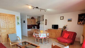 Una sala de estar acogedora con un sofá de madera, una mesa de centro de vidrio y una mesa de comedor con sillas.