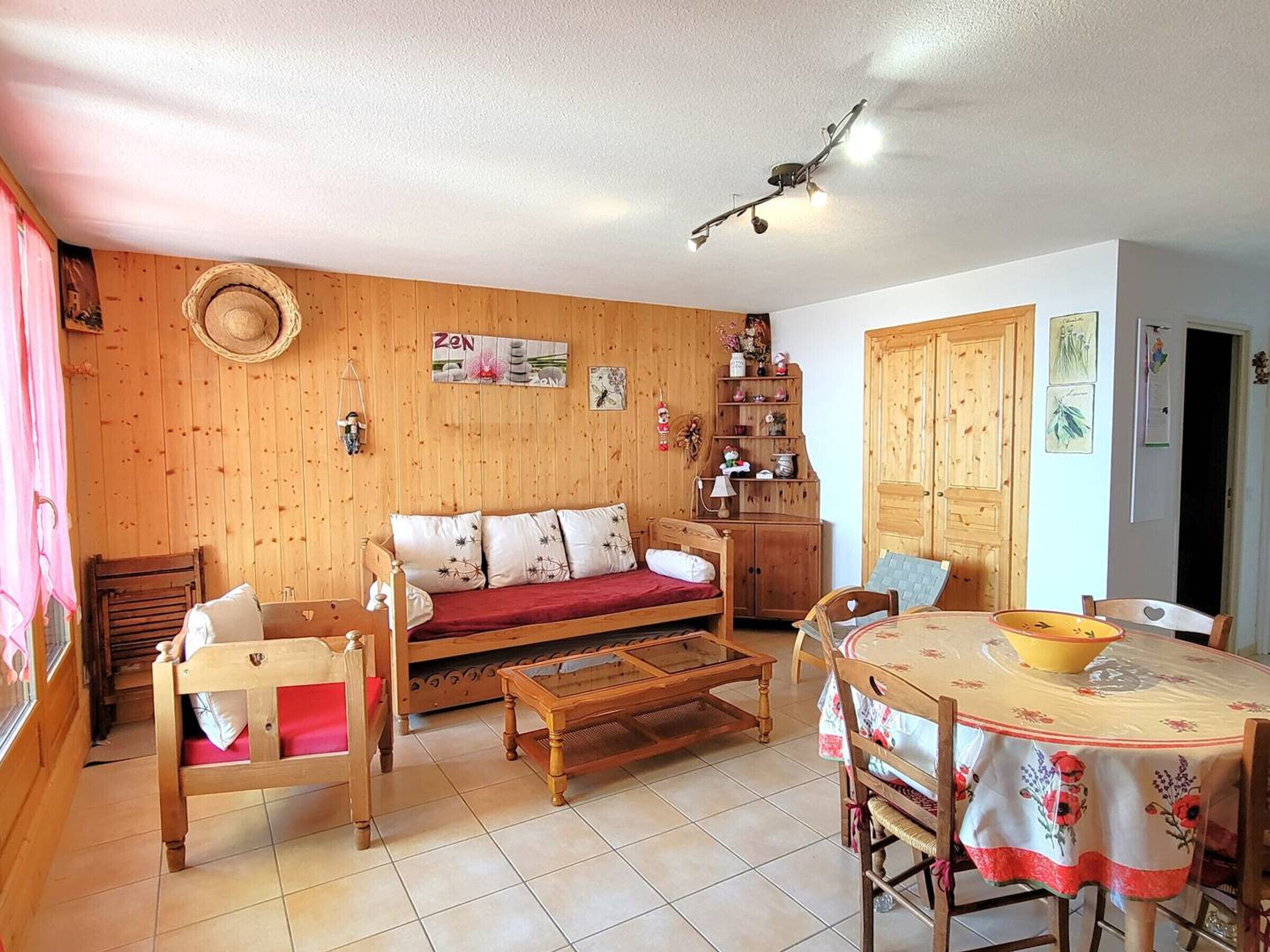 Une pièce chaleureuse avec un plancher en bois, un canapé, une table en bois et une table à manger avec des chaises.