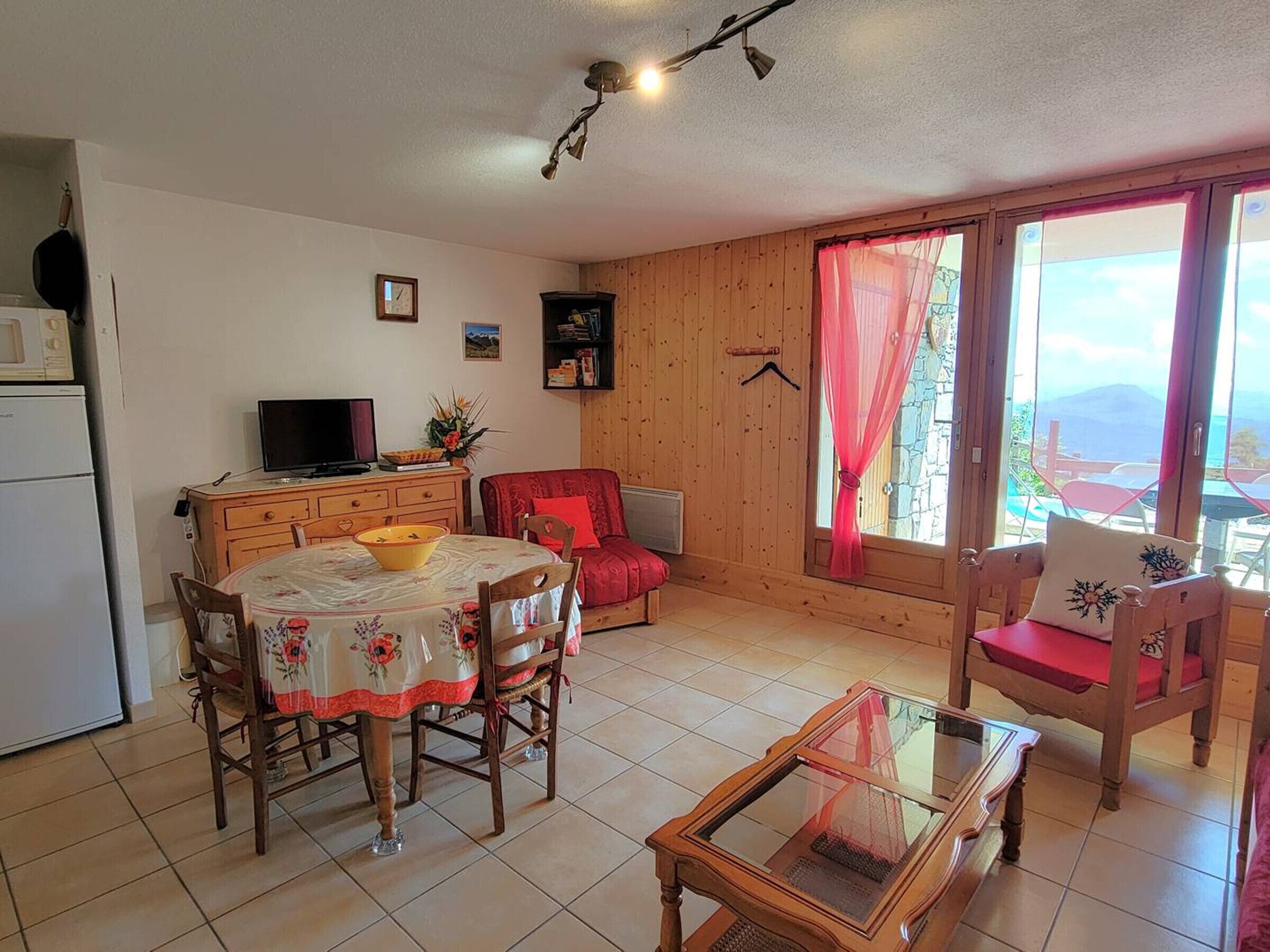 A cozy room with a dining table, chairs, a television, and a view of the outdoors.
