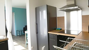 A compact kitchen with a stainless steel refrigerator, a built-in oven, and a modern range hood.