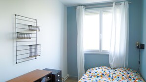 A bedroom with a bed, a desk, and a wall-mounted shelf unit.