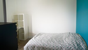 A bedroom with a bed, a desk, and a wardrobe.