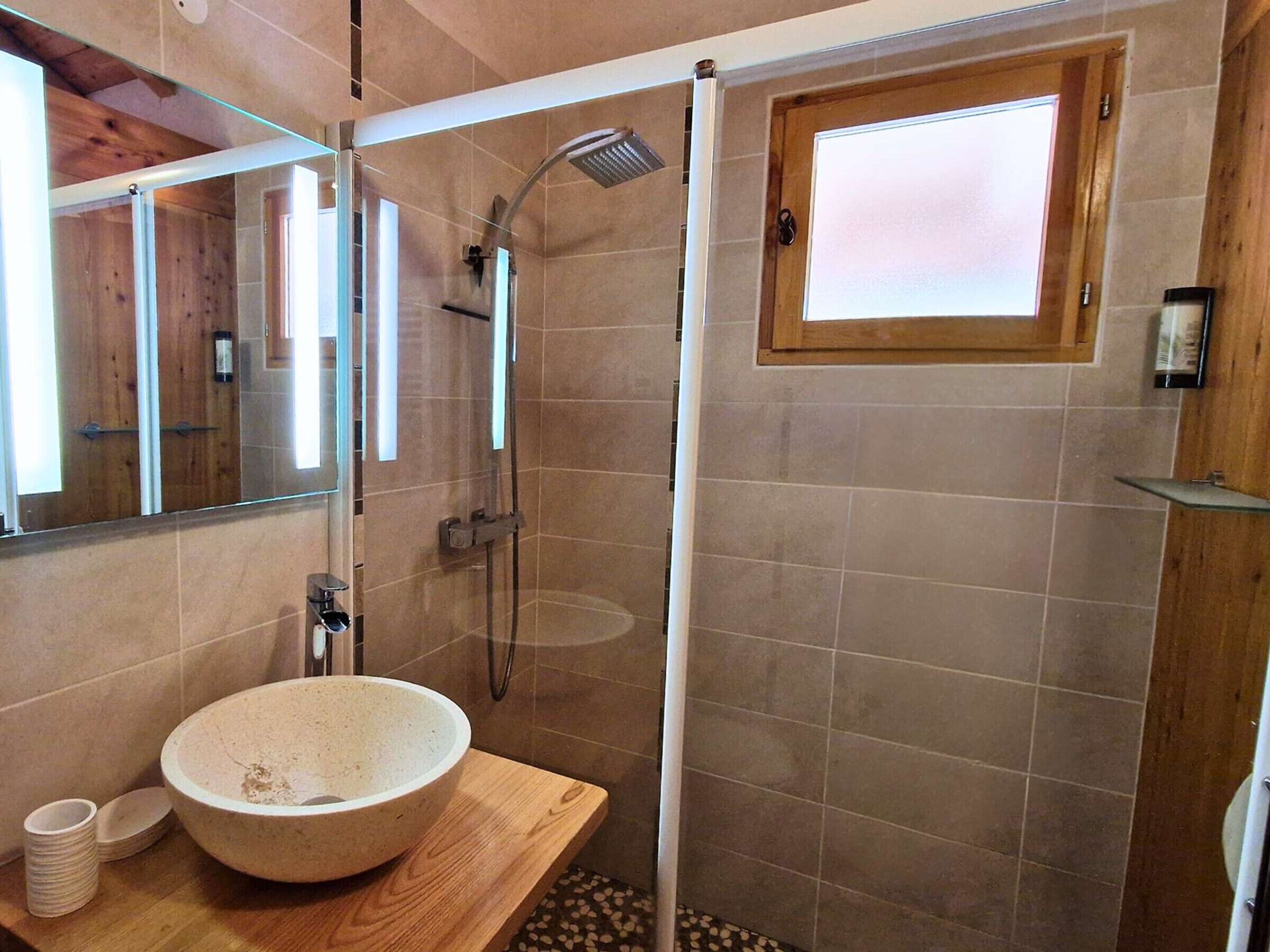 Un baño moderno con un lavabo grande, una ducha y una ventana.