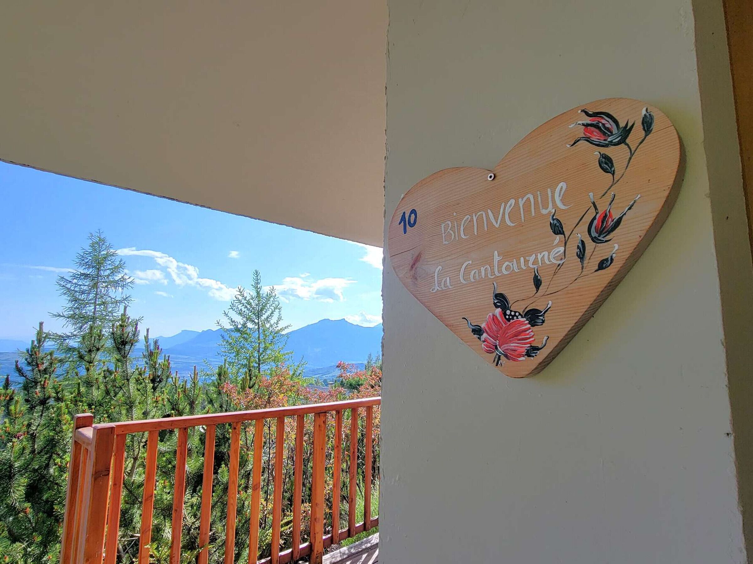 A wooden heart-shaped welcome sign with a scenic mountain view in the background.