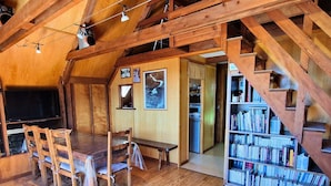 Un intérieur en bois comprenant une table à manger, des chaises, une bibliothèque et un escalier.