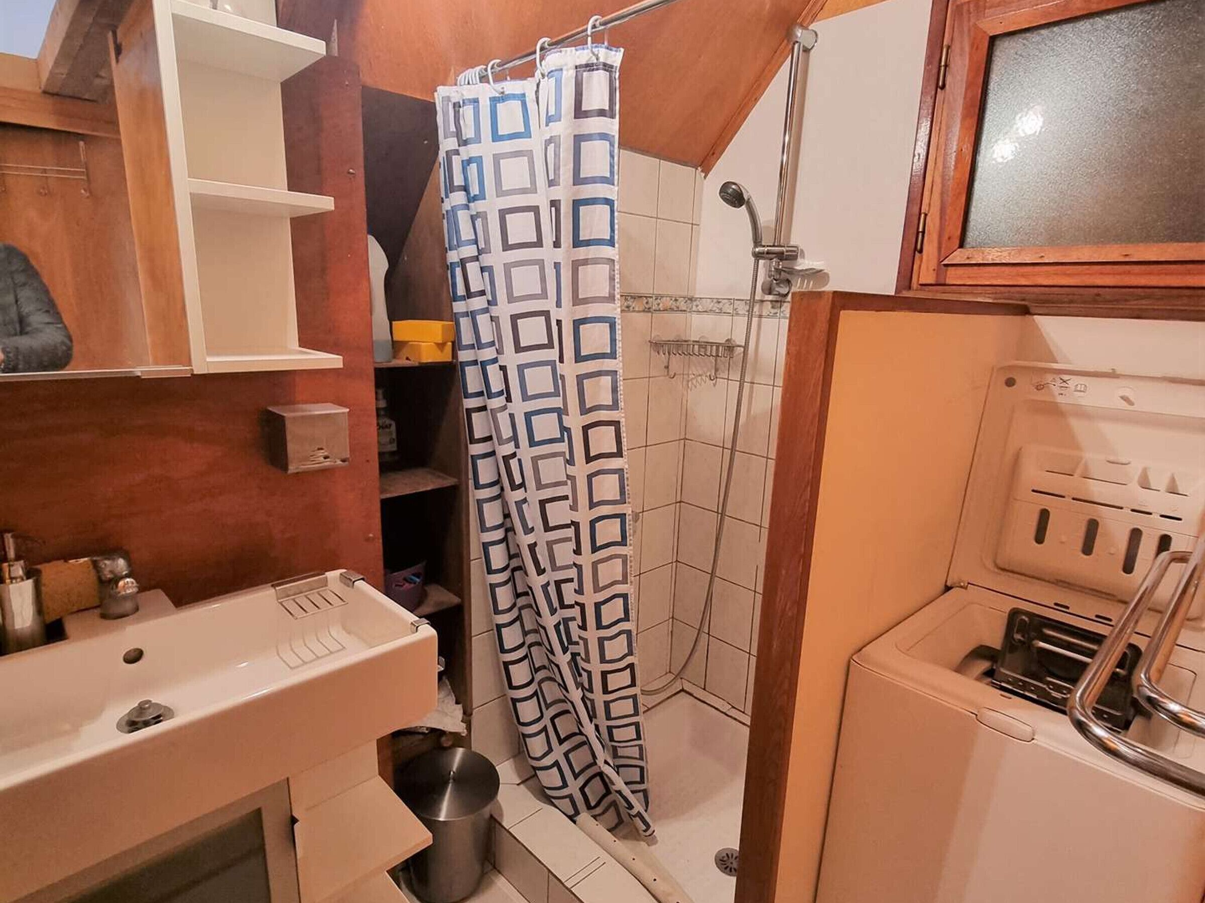 A compact bathroom with a shower, a sink, and a cabinet.
