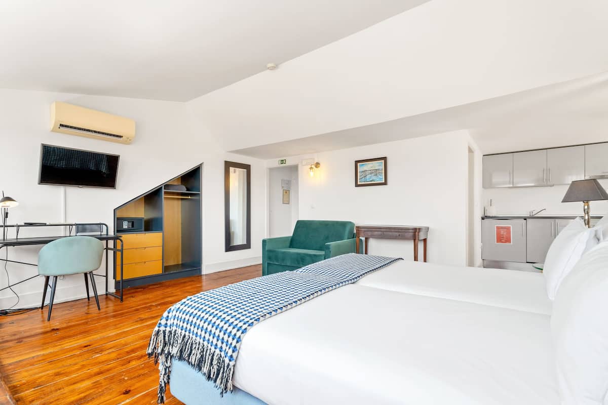 Een hotelkamer met een bed, een bureau, een stoel, een televisie en een kitchenette.