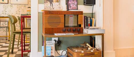 A vintage radio on a wooden shelf, surrounded by books and a decorative vase.