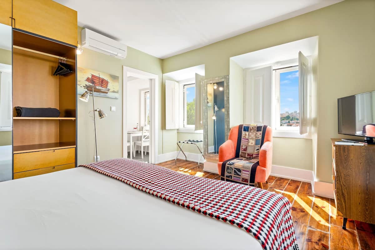 Hotelkamer met een bed, een stoel, een bureau, een airconditioning en een raam met uitzicht.