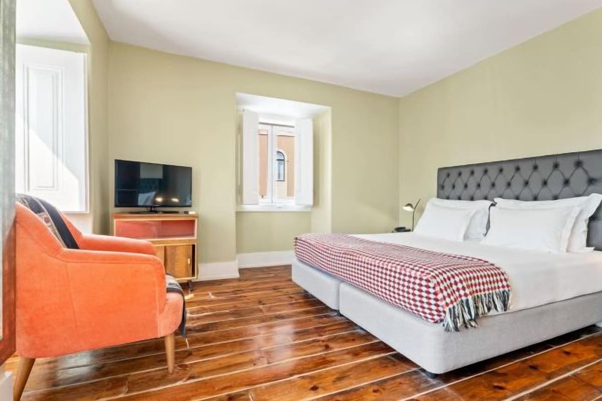 Une chambre d’hôtel avec un lit, une télévision, une chaise et une fenêtre.