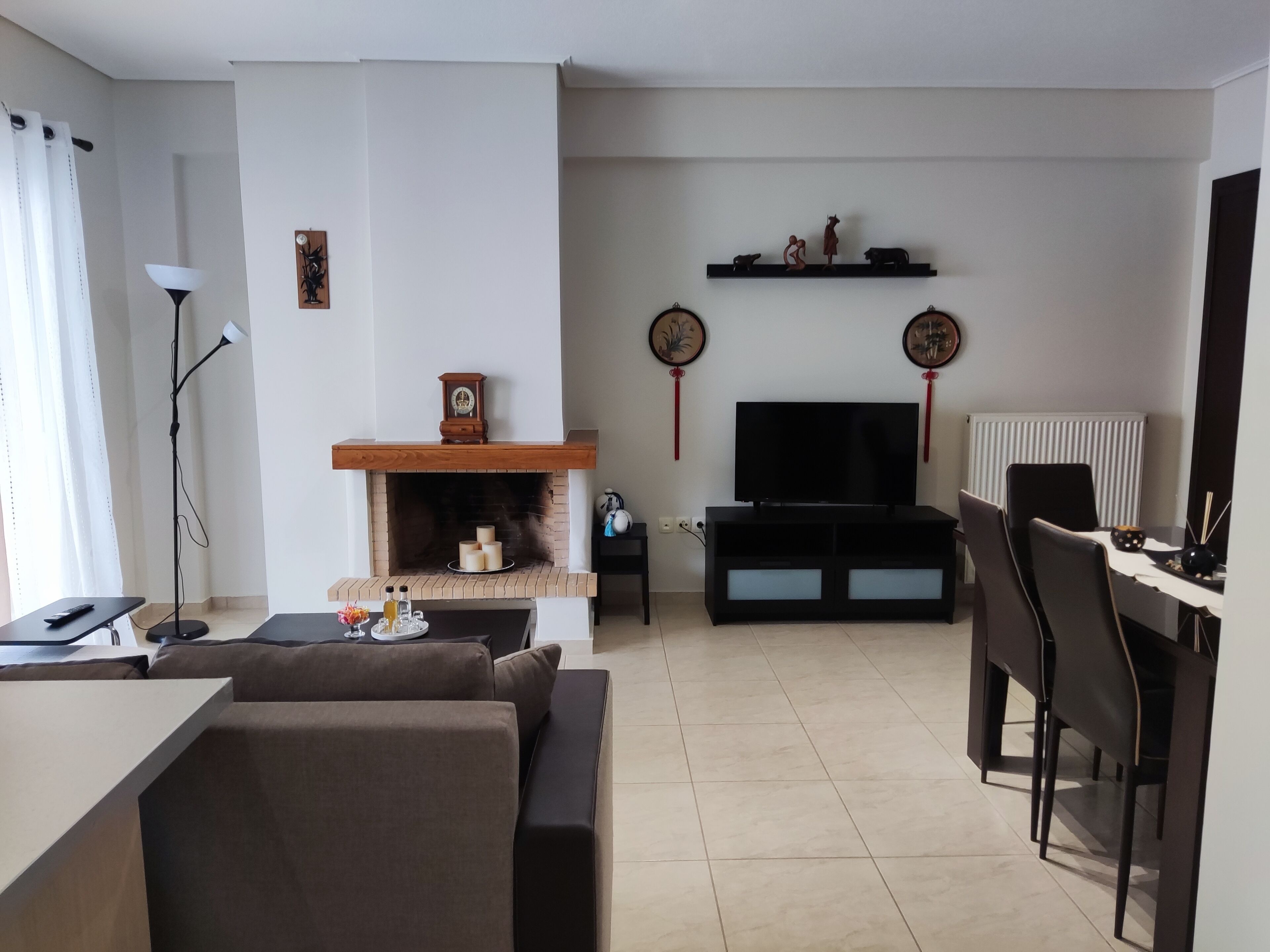 A living room with a fireplace, a TV, and a dining area with chairs and a table.