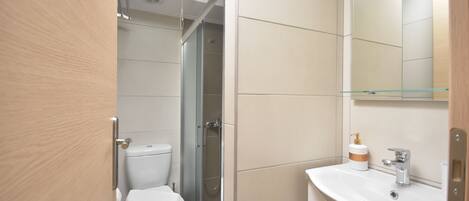 A modern bathroom with a toilet, shower, and sink.