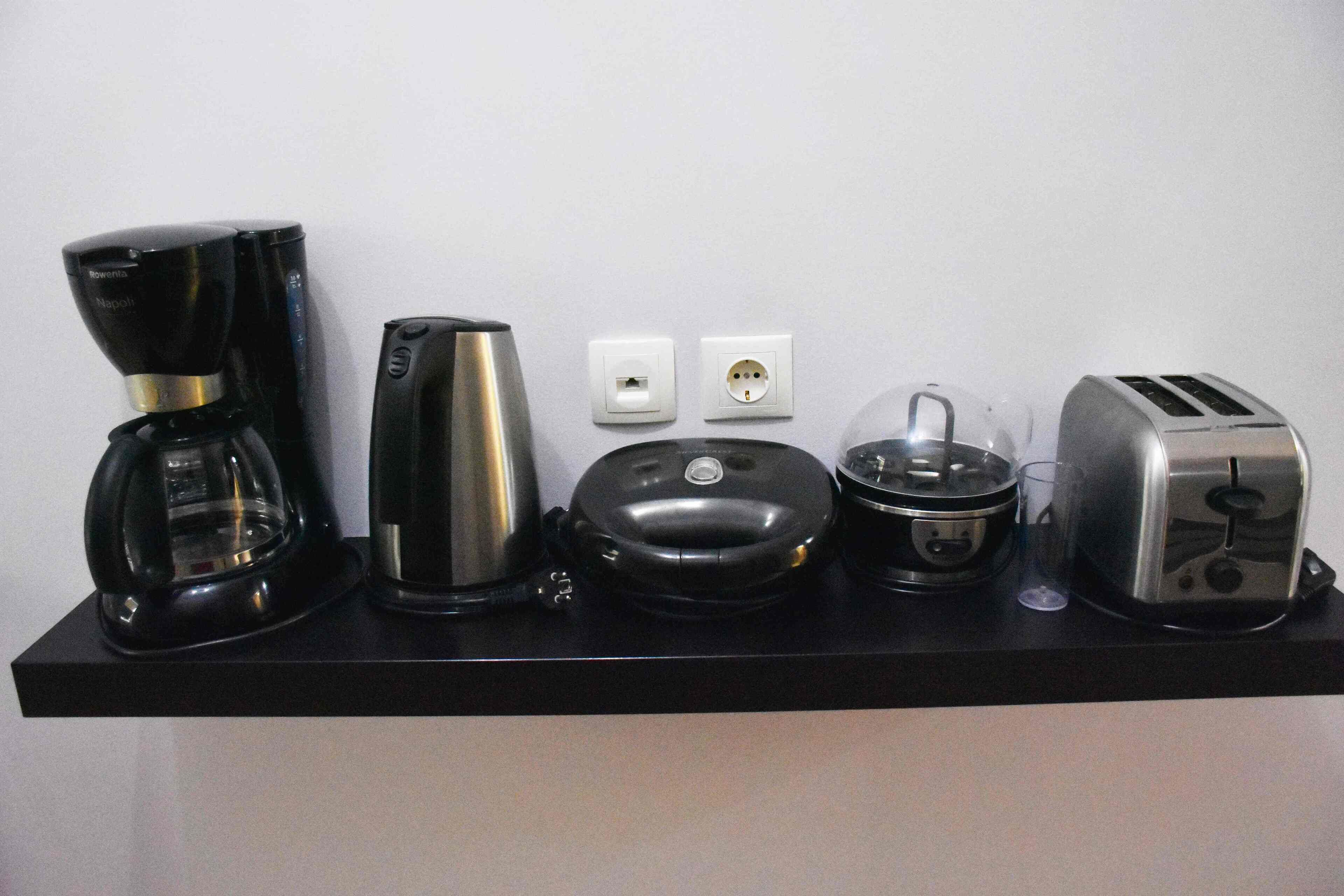 Eine Küchenarbeitsplatte mit Kaffeemaschine, Wasserkocher, Toaster und einem Glas.