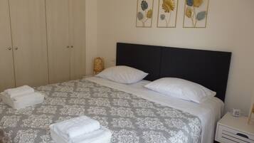 Een net opgemaakt bed met een beddekleed met patroon, twee kussens en een nachtkastje met een lamp.