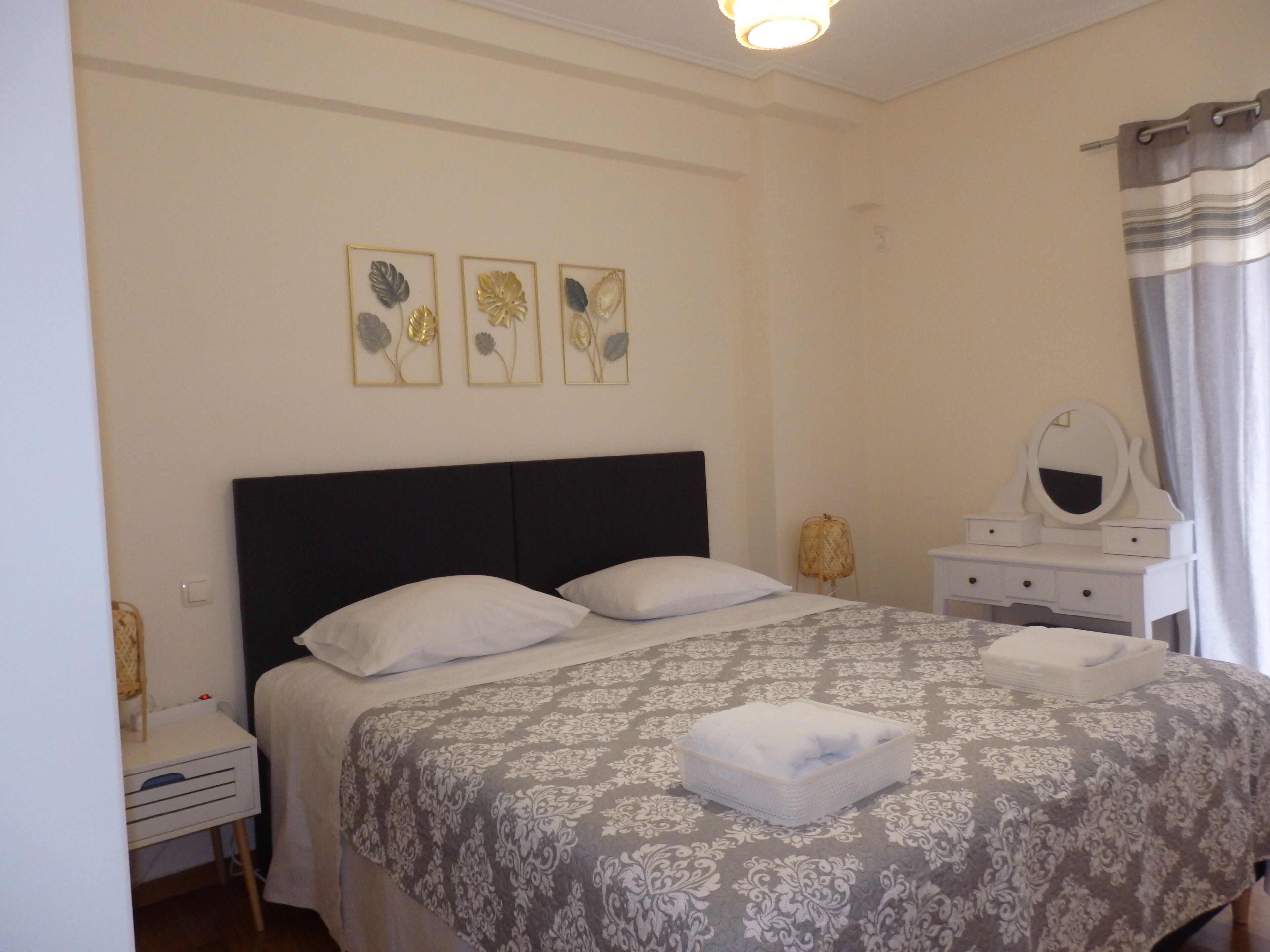 Une chambre à coucher bien rangée, avec un lit, des tables de chevet, une commode et un miroir.