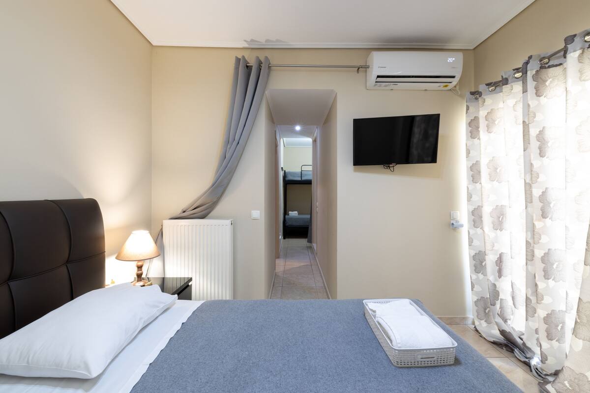 Een hotelkamer met een bed, een bedlamp, een airconditioner, een televisie en een badkamer die door een deuropening zichtbaar is.