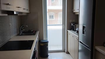Una cocina moderna con un lavamanos de acero inoxidable, un cubo de basura negro y un refrigerador.