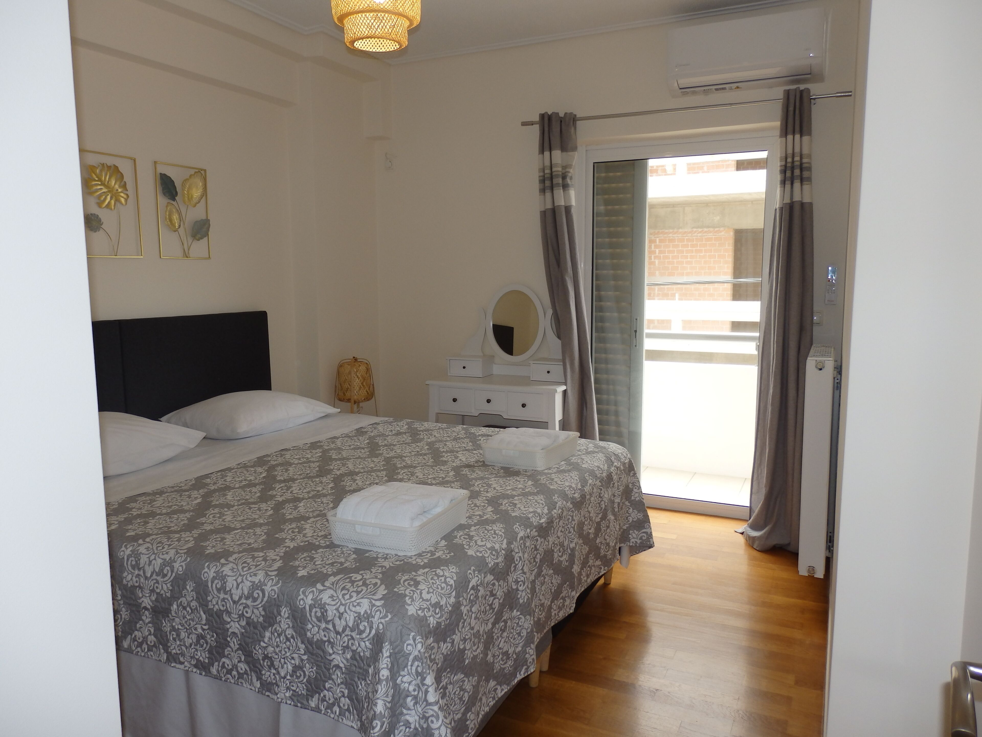 A bedroom with a bed, a dresser, a mirror, and a window with curtains.