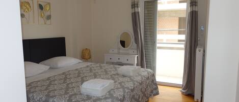 A bedroom with a bed, a dresser, a mirror, and a window with curtains.