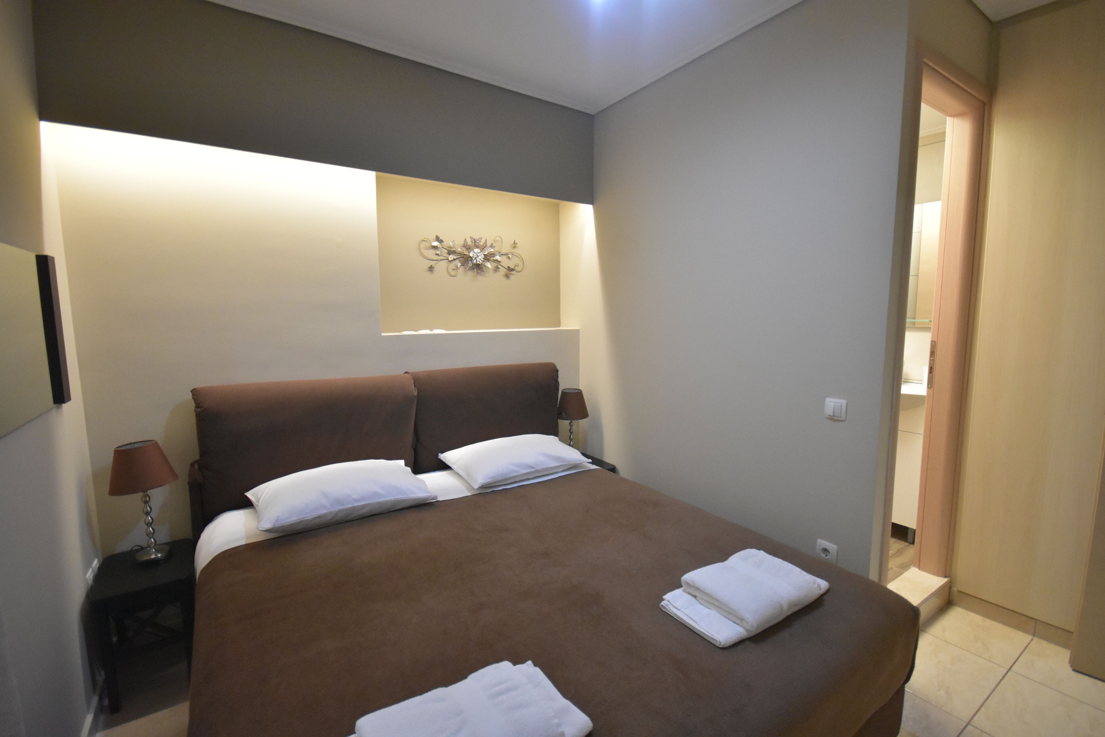 Een slaapkamer met een groot bed, twee nachtkastjes en een wandlamp.