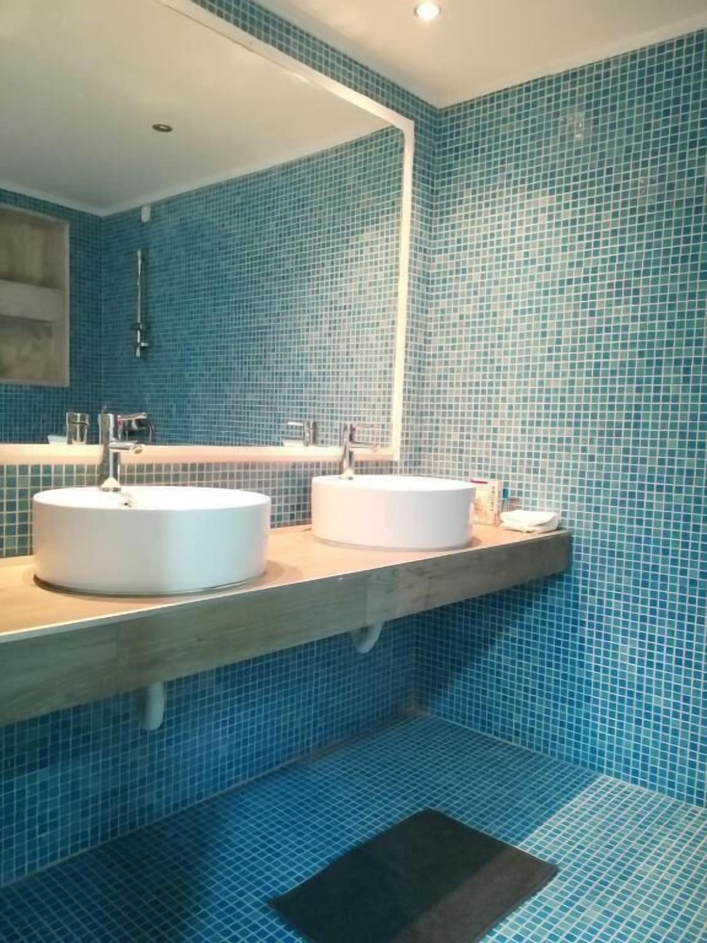 A bathroom with two sinks, a wooden countertop, and blue-tiled walls.