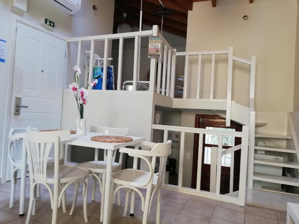 A dining area with white chairs and a table, a white staircase, and a view of the outside.