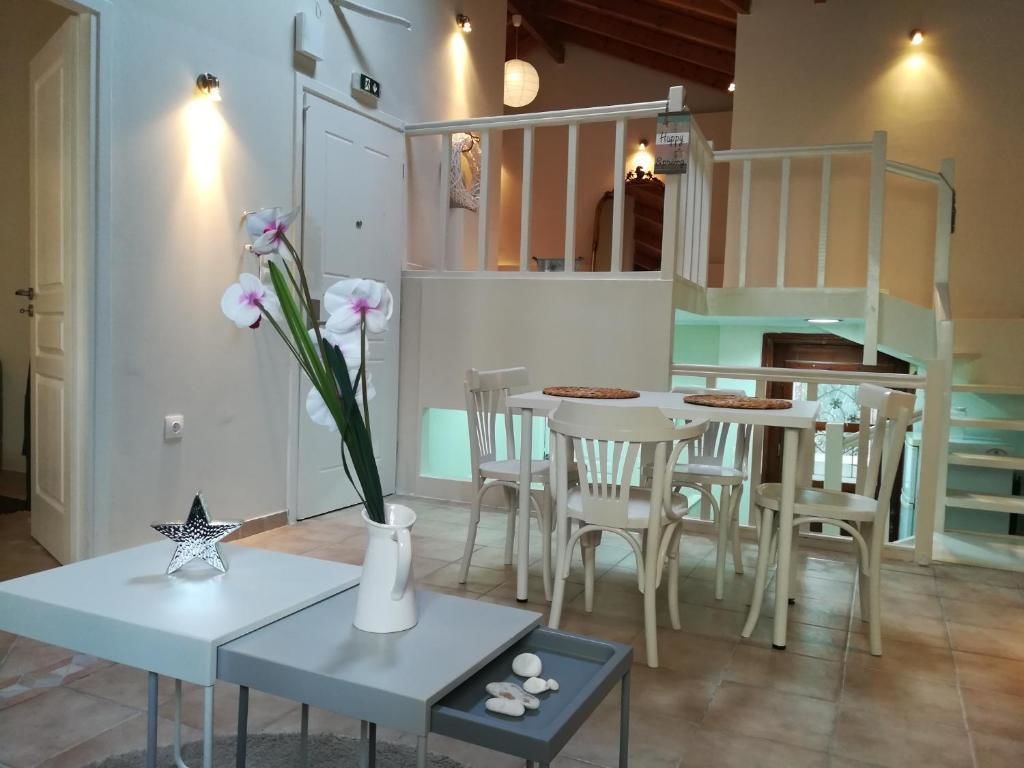 Ein Essbereich mit Tisch und Stühlen, einer Vase mit Blumen und einer Treppe im Hintergrund.