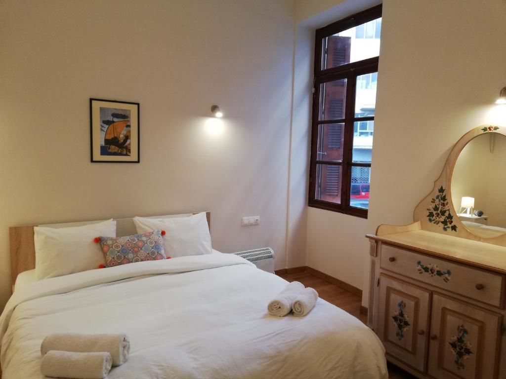 A bedroom with a bed, a dresser with a mirror, a window, and a wall-mounted picture.