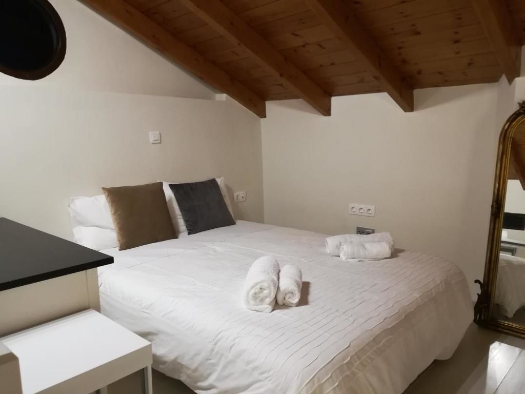 Quarto com cama, mesa de cabeceira, espelho e teto com vigas de madeira.
