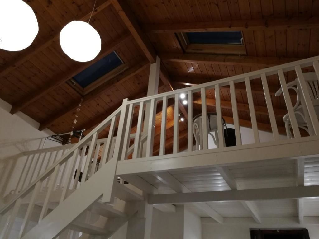 Un intérieur en bois avec un escalier blanc et un balcon.