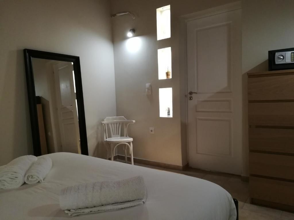 A bedroom with a bed, a mirror, a chair, a wardrobe, and a door with windows.