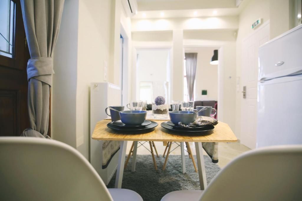 Een smalle gang met een houten tafel gedekt voor twee personen, twee stoelen en een witte koelkast.