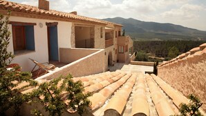 A traditional building with a terracotta roof, a balcony, and a view of the surrounding landscape.