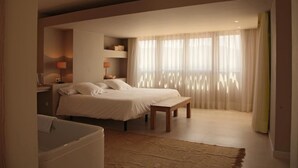 A bedroom with a bed, bedside tables, a bench, and a window with curtains. - Aldea Roqueta Hotel Rural (Culla)