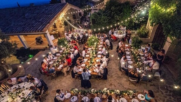 An outdoor dining area with stone tables and chairs, surrounded by greenery and string lights. - Aldea Roqueta Hotel Rural (Culla)
