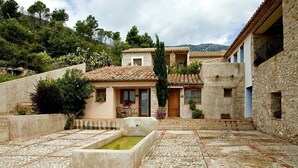 A courtyard with stone flooring, a central water feature, and buildings with traditional architecture. - Aldea Roqueta Hotel Rural (Culla)