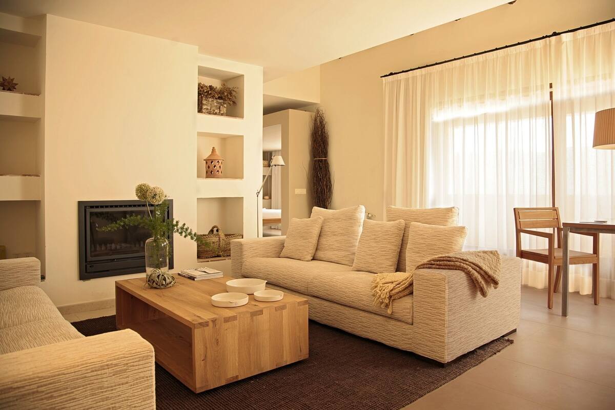 A living room with a beige sofa, a wooden coffee table, and a fireplace.