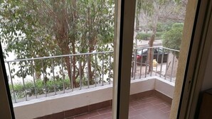 Een balkon met betegelde vloer en metalen hekwerk.