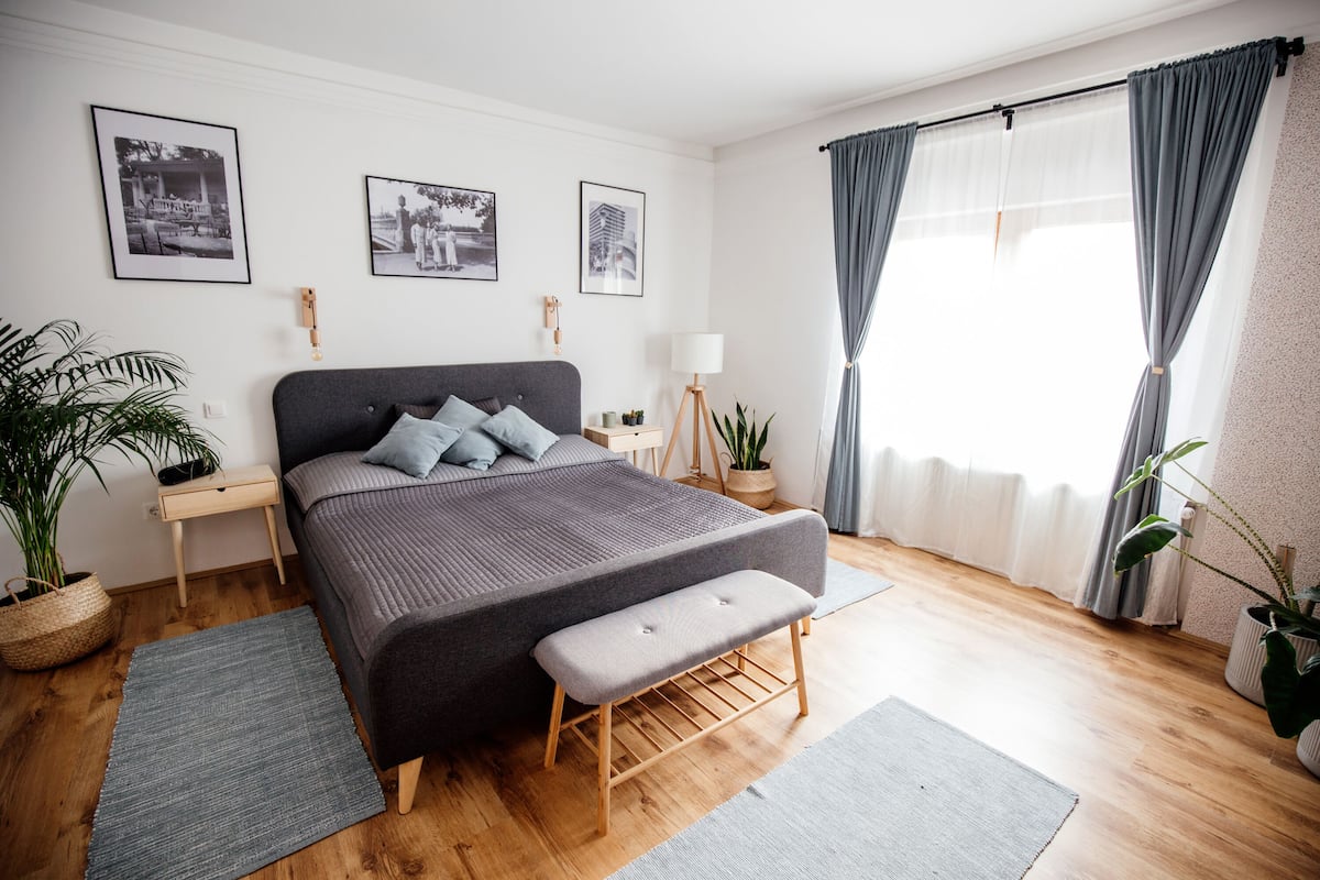 Ein modernes Schlafzimmer mit einem großen Bett, Nachttischen, einer Bank und gerahmten Bildern an der Wand.