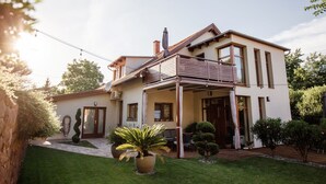 A two-story house with a balcony, a garden, and a clear sky. - Csendeskert Apartments (Balatonalmadi)