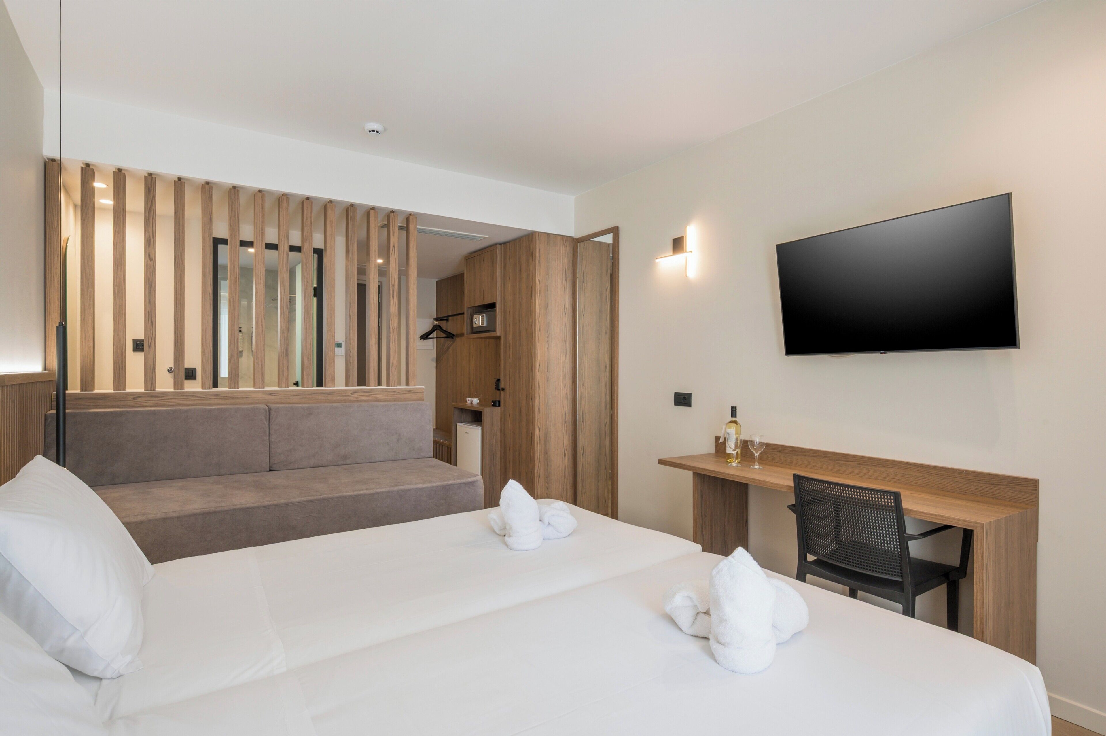 Une chambre d’hôtel moderne équipée d’un lit, d’un bureau, d’une télévision et d’un escalier menant à un placard.